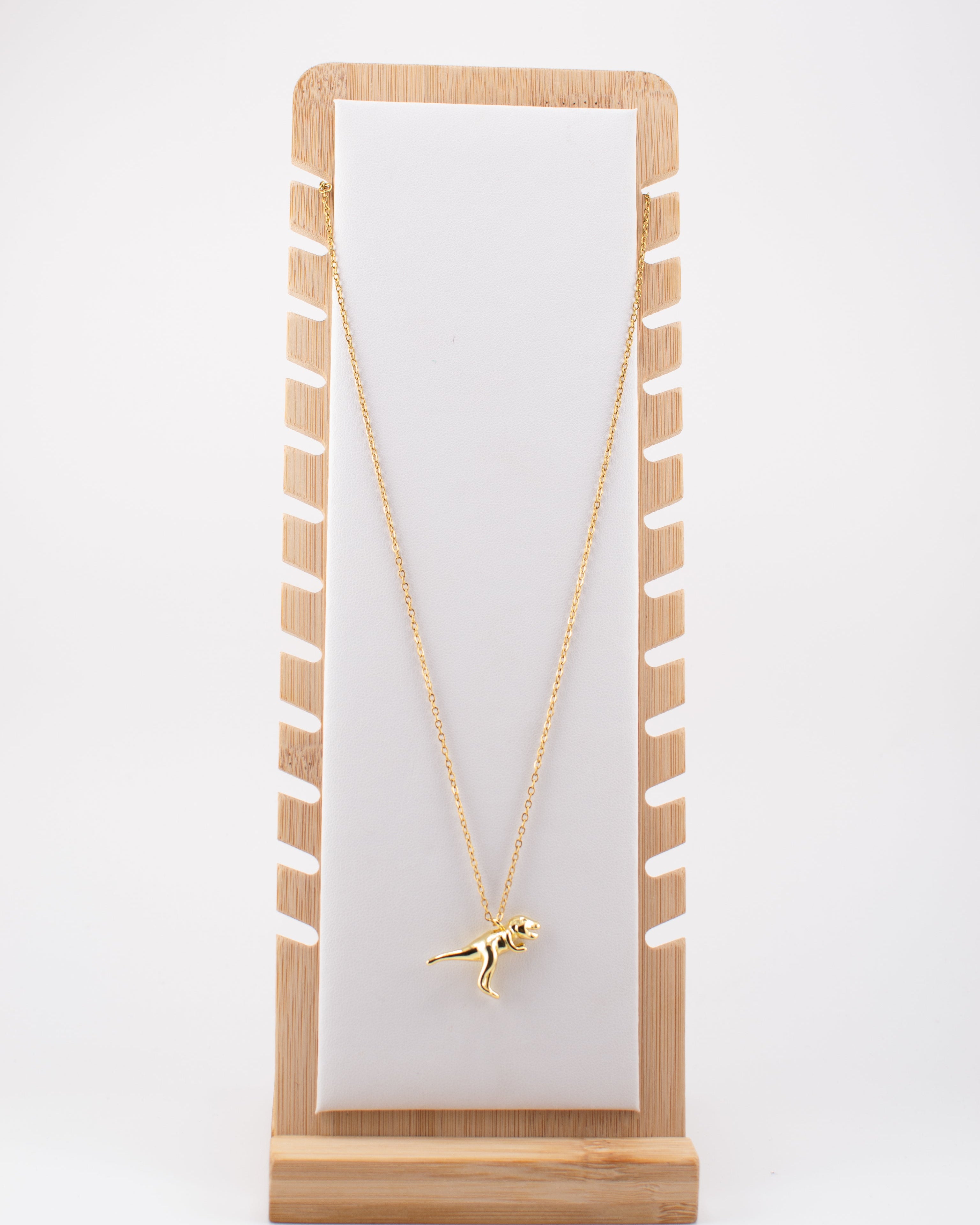 Gold necklace on a white card with wooden stand against a white background